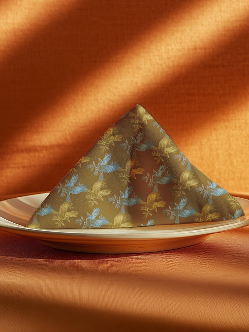 Set of four golden cloth napkins featuring alternating powder blue and metallic gold ravens in flight, sized 18x18 inches.